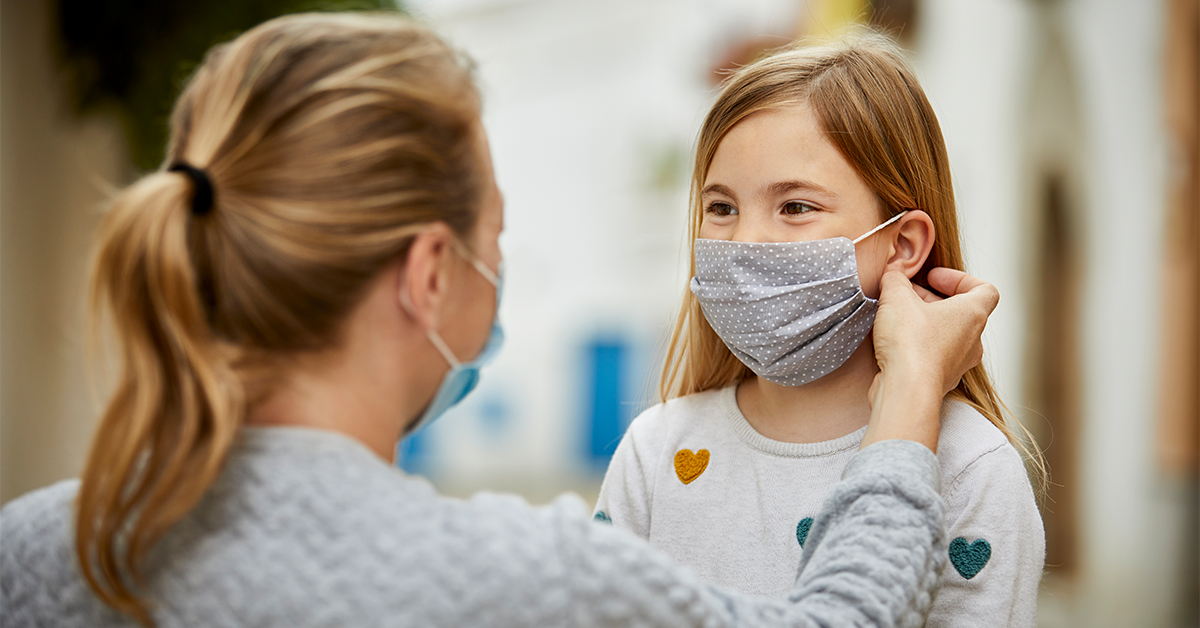 Woman putting on a cloth face mask on a child