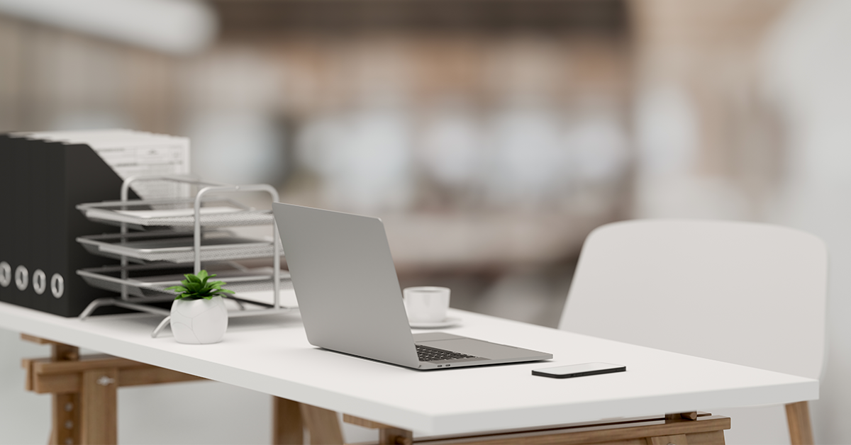 An empty desk with a laptop and cell phone